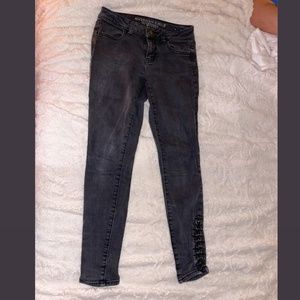 Black-gray stretchy skinny jeans/jeggings with gold embellishments at the bottom